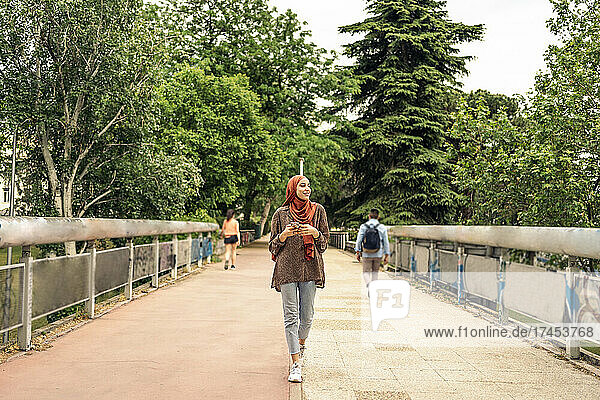 muslim woman walking while using a phone