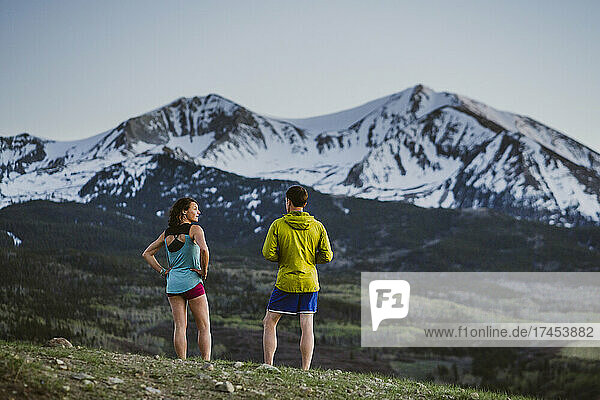 Two friends catch their breath while running in front of large peak