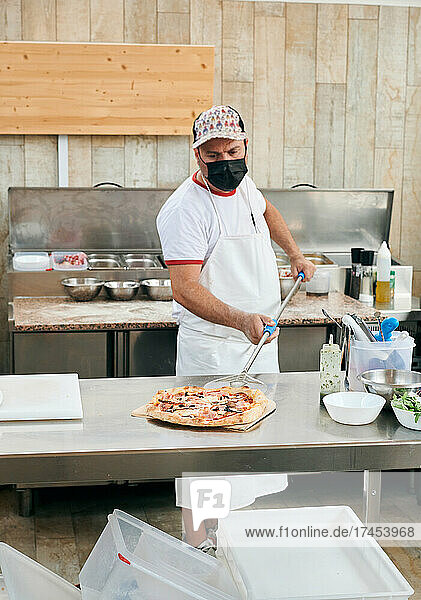Cook prepares a pizza in a restaurant kitchen