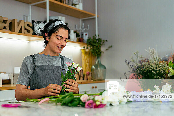 A young florist putting together a bouquet of flowers in her studio
