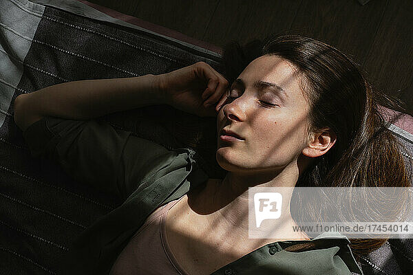 Portrait of young woman sleeping in bed in sunny rays