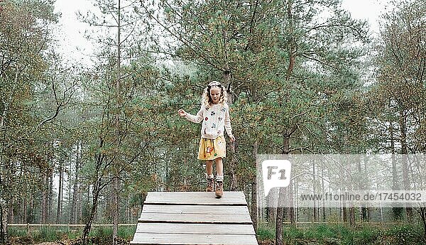 girl walking down a wooden ramp in the forest in autumn