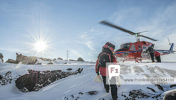 A scientist carries samples to a helicopter on a volcano in Antarctica