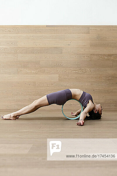 Young flexible woman doing purvottanasana yoga pose with wheel