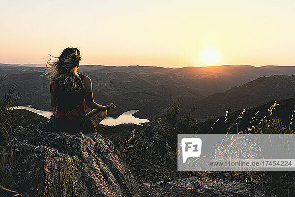 A woman sitting in lotus meditation position on a beautiful sunset.