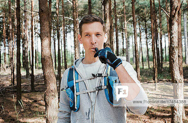 man drinking from a bladder in his running vest whilst in the forest