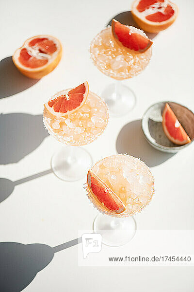 Pink grapefruit margarita cocktails on white background with shadows