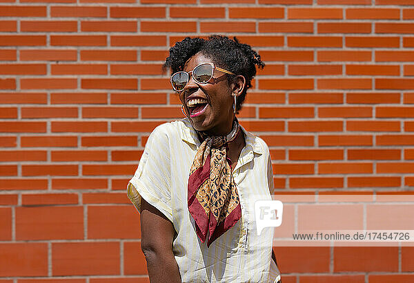 Happy African American female against brick wall