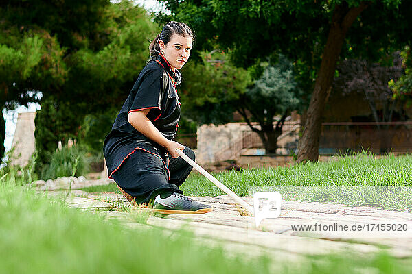Woman training kung fu with a stick in a park