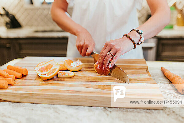 Close up of woman cutting oranges on cutting board in her kitchen