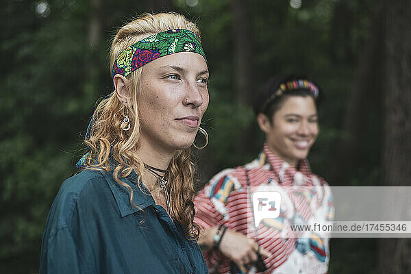 Young blond bohemian woman with bandana and Asian friend in nature