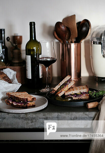 Meat and pickles sandwiches and glass of red wine on concrete table