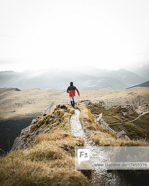 Man in red jacket waliking on a mountain path
