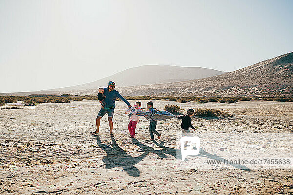 Father and children playing at Fuerteventura beach having fun vacation