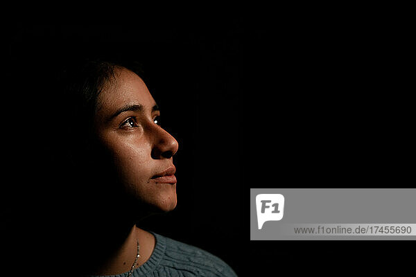 Portrait of Hispanic woman looking aside in the dark