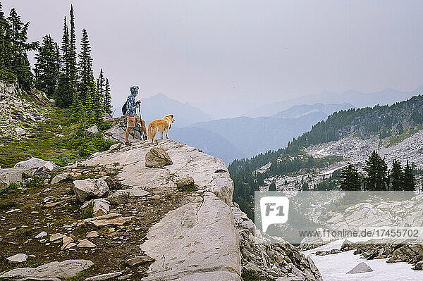 Male hiker and dog standing on a cliff in the north cascades