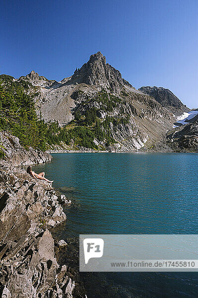 Fit Girl In Bikini Tanning Next To Beautiful Blue Colored Alpine Lake