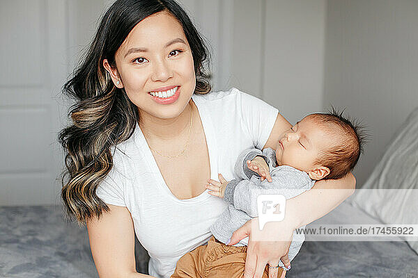 Mothers day. Proud smiling Chinese Asian mother with newborn baby