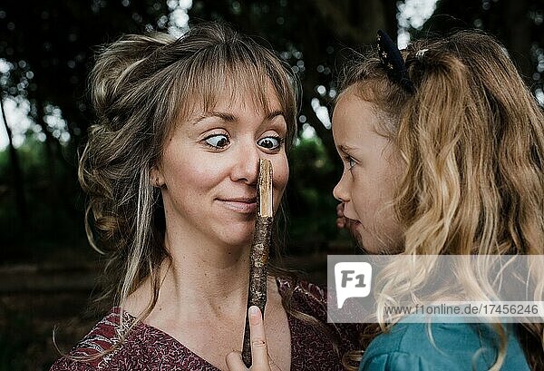 daughter playing funny faces with sticks with mother cross eyed