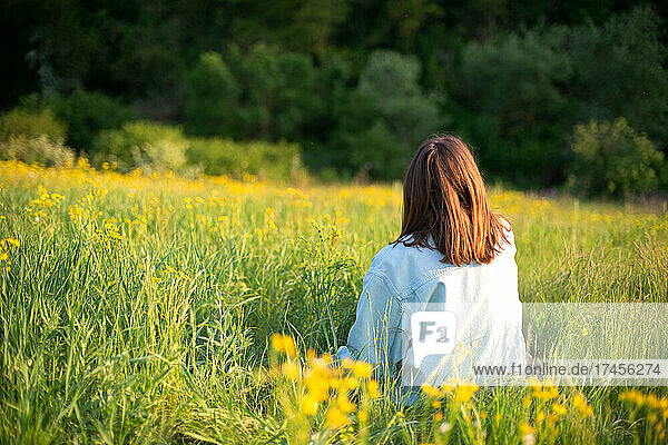 Portrait of confident young woman sitting in field