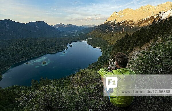 Young man looking over the Eibsee lake at sunset  Zugspitze and Zugspitzmassiv  alpenglow  behind Bishop and Krottenkopf  Wetterstein Mountains  near Grainau  Upper Bavaria  Bavaria  Germany  Europe