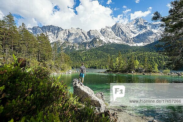 Young man standing on a rock  view into the distance  Eibsee lake and Zugspitze in spring with snow  Wetterstein Mountains  near Grainau  Upper Bavaria  Bavaria  Germany  Europe