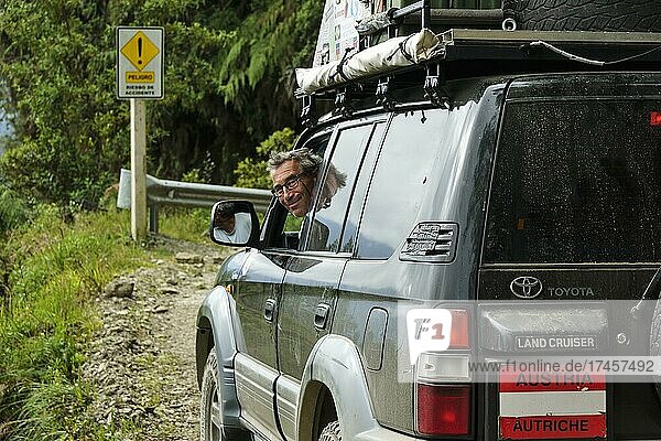 Driver smiling from an off-road vehicle  Toyota Land Cruiser  on the road of death  Camino de la Muerte  La Paz Department  Bolivia  South America