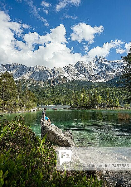 Young man sitting on a rock  view into the distance  Eibsee lake and Zugspitze  Wetterstein Mountains  near Grainau  Upper Bavaria  Bavaria  Germany  Europe