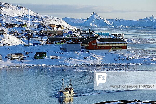 Fischerboot vor Häusern und Eisbergen in winterlicher Landschaft  Ilulissat  Diskobucht  Westgrönland  Nordamerika  Dänemark  Europa