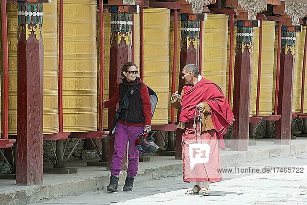 Europäische junge Frau unterhältt sich mit einem tibetischen Mönch bei der morgendlichen Umrundung  tibetisch: Kora eines tibetischen Klosters im Grasland von Tagong  Kloster Lhagang  Lhagang Gompa  Tagong  Sichuan  China  Asien