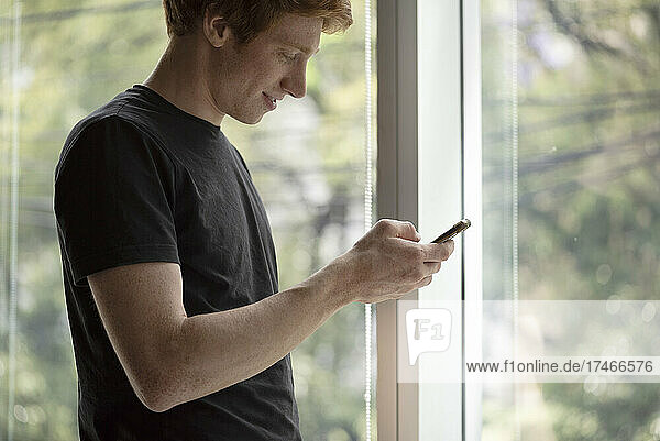 Smiling young man using smart phone