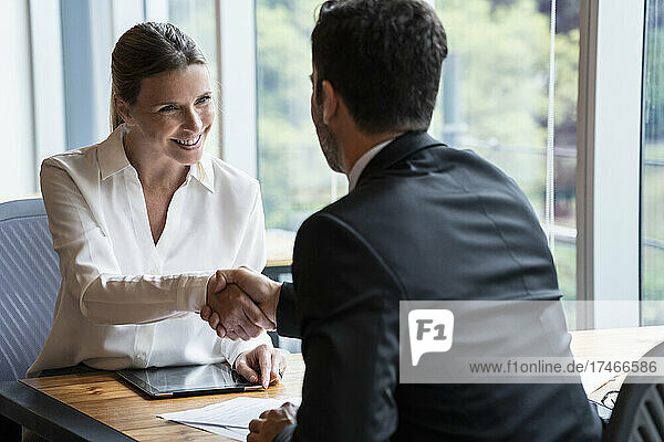 Businesswoman shaking hands with businessman during meeting