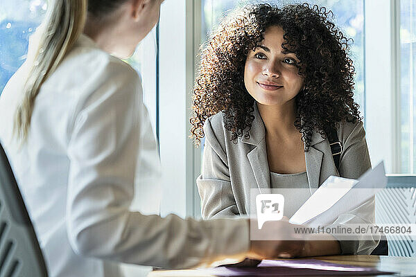 Young woman talking to mature woman in office