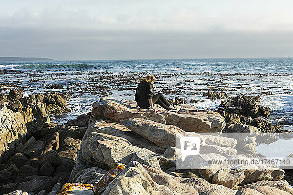 Teenage girl walking across jagged rocks  exploring rock pools by the ocean