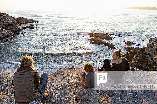 Eine Familie  Mutter und zwei Kinder  die den Sonnenuntergang über dem Meer beobachten.