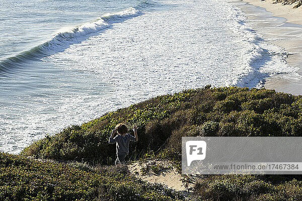 A boy running excitedly down a path to the beach