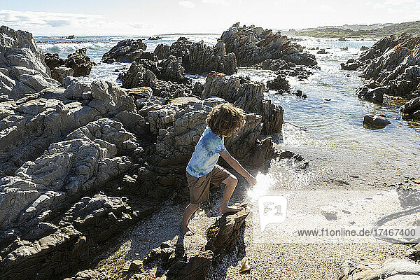 Achtjähriger Junge erkundet einen felsigen Strand