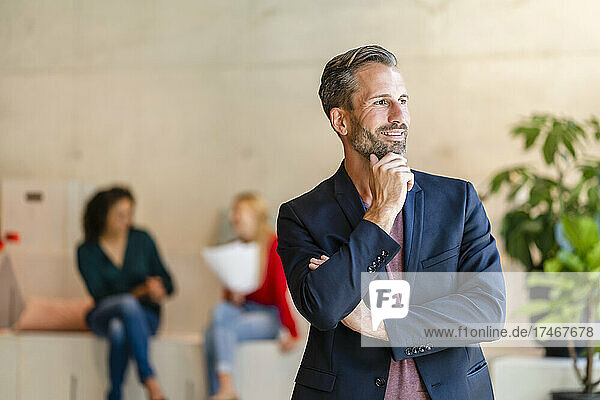 Thoughtful businessman with hand on chin in office