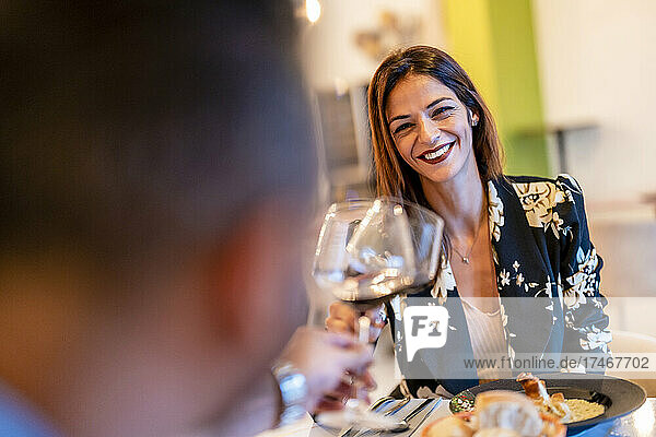 Lächelnde Frau prostet Weinglas mit Mann im Restaurant an