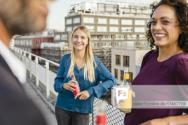 Blond businesswoman having drink with colleagues at rooftop
