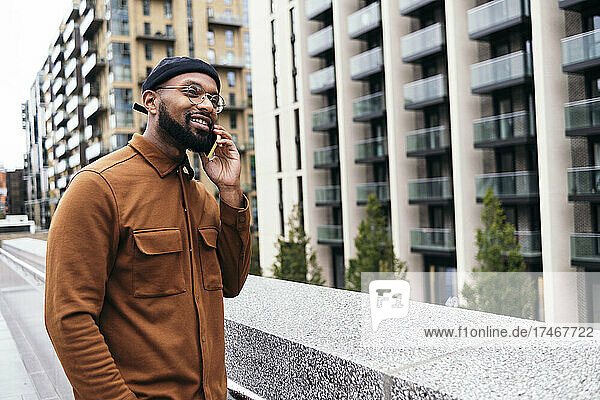 Smiling man talking on mobile phone in city