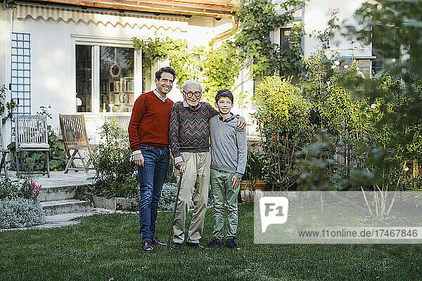 Smiling senior man with son and grandson in backyard