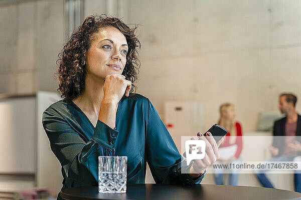 Thoughtful businesswoman with hand on chin at workplace