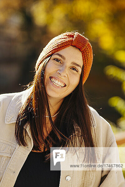 Smiling beautiful young woman with knit hat on sunny day