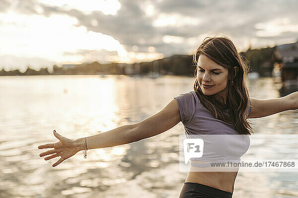 Mid adult woman with brown practicing yoga by lake
