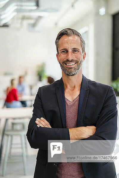 Businessman standing with arms crossed in office