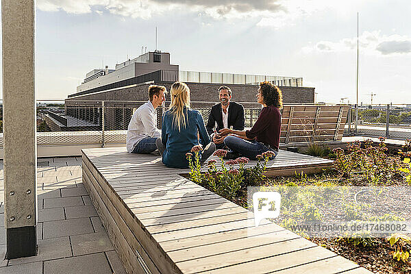 Coworkers with cross-legged sitting on rooftop