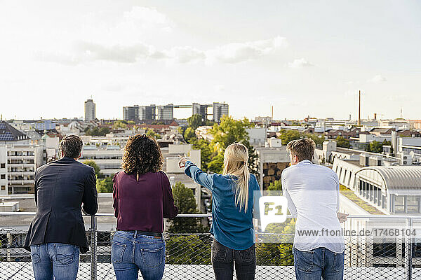 Kollegen schauen auf das Stadtbild  während sie auf dem Dach stehen