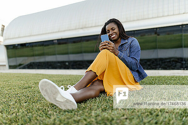Young woman using smart phone sitting on grass