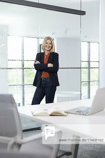 Smiling businesswoman standing with arms crossed in office